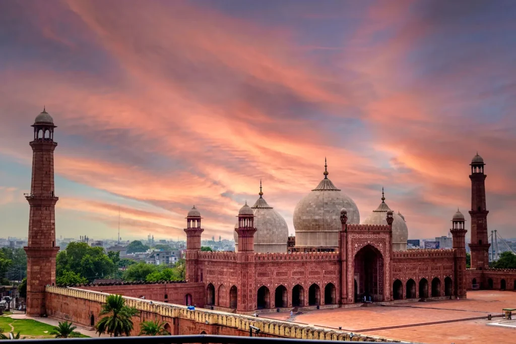 The Badshahi Mosque in Lahore, Pakistan, under a pink and orange sunset sky