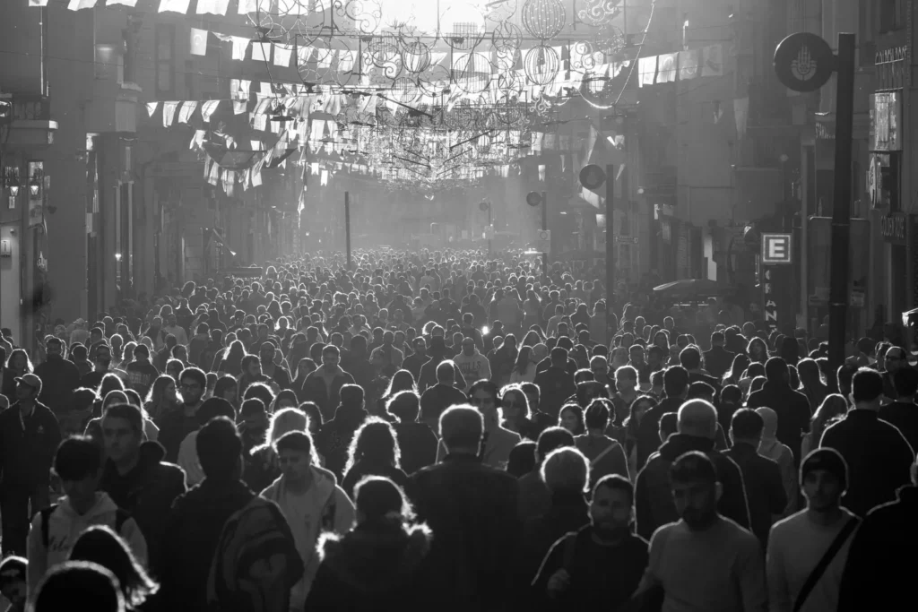 A dense crowd of people filling a city street, photographed in black and white