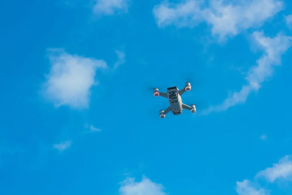 A small unmanned drone flying against a bright blue sky