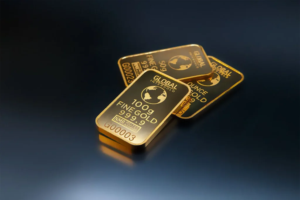 Two bars of fine gold lying on a dark reflective surface
