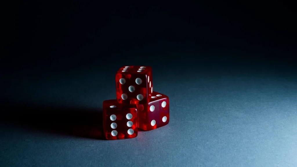 Three red translucent dice stacked on a dark surface, a symbol of chance and risk